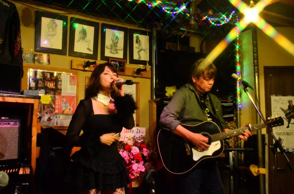 蒔田アビームのステージで演奏する本牧シンガーのんとみっちぃ、Re:Ze.10周年のフラワースタンド