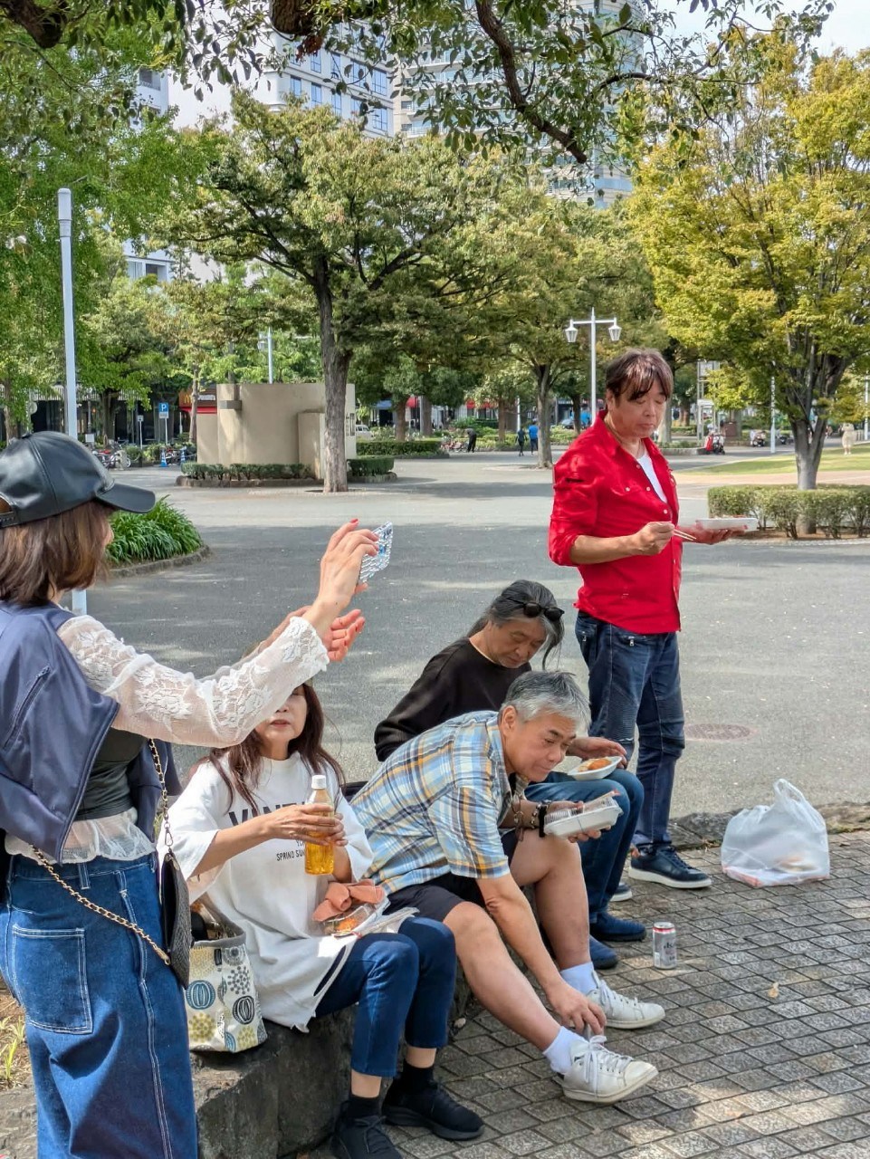 横浜マリンタワー前で赤いシャツを着てギターを弾くみっちぃと、近くで見守る人たち