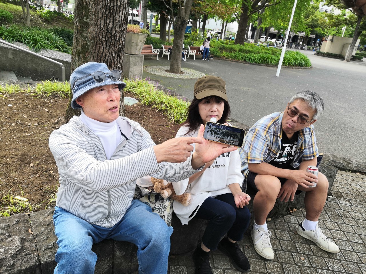 横浜マリンタワー前でストリートライブを聴く人たちの写真